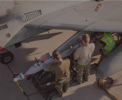 RAF Weapon Technicians uploading guided bomb to Typhoon on concrete apron