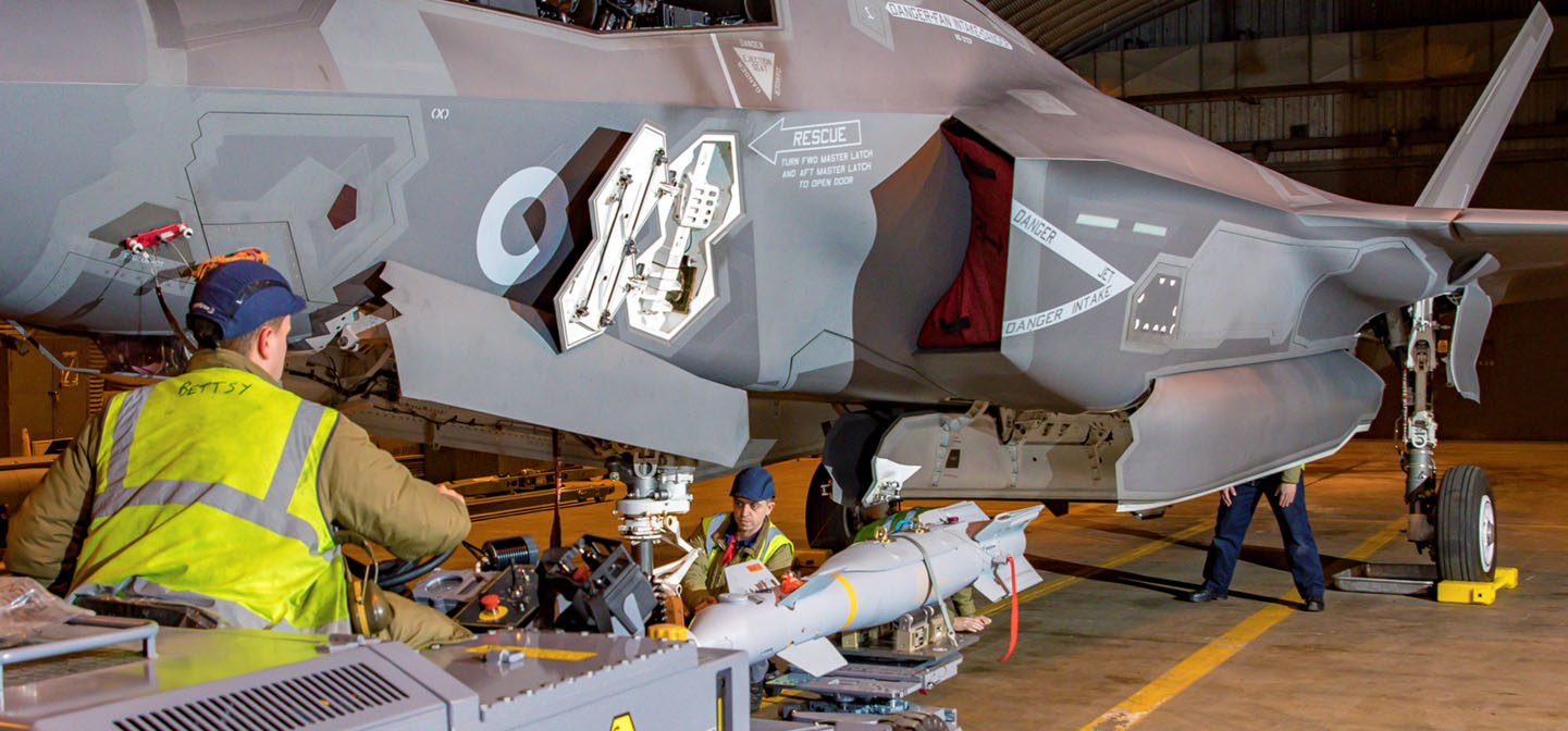 Weapons technicians loading bomb to F-35 in hangar