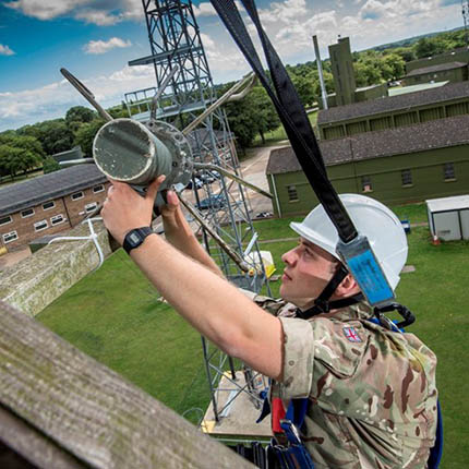 RAF Communication Infrastructure Technician in safety harness working on elevated mast installing antenna