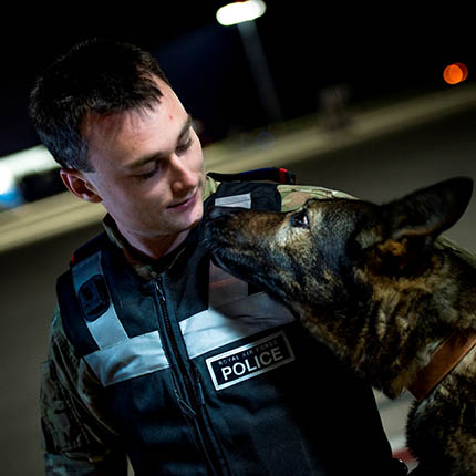 RAF Police Officer with police dog on airfield at night