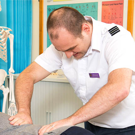 RAF Physiotherapist manipulating patient's back in treatment room