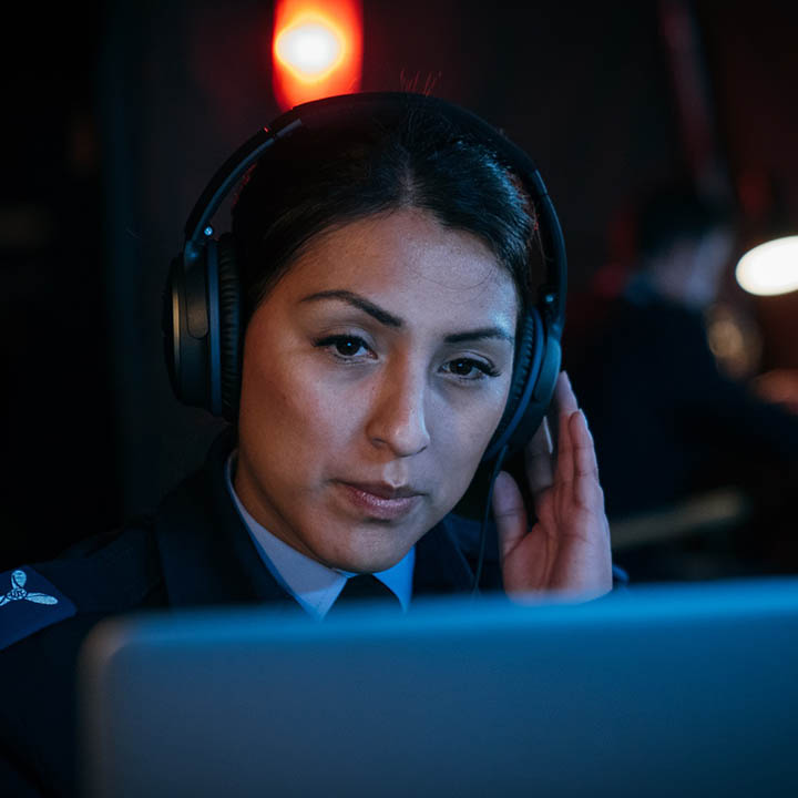 Female RAF Intelligence Analyst (Voice) sat at workstation listening to audio conversation with headphones