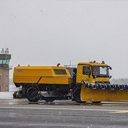 RAF Driver operating snow-plough and sweeper truck on airfield during snow storm