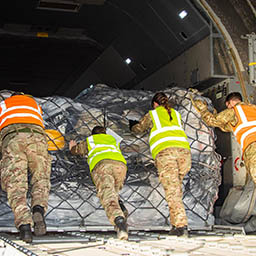 RAF Movers pushing netted pallet of cargo into aircraft load bay