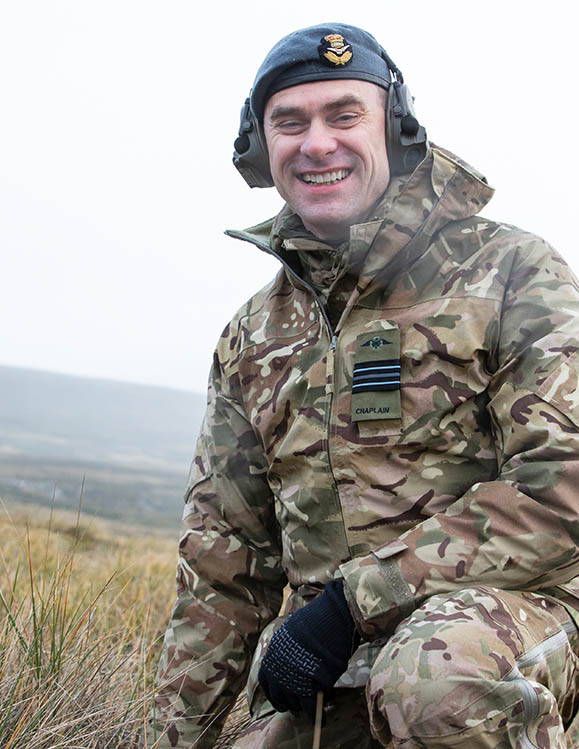 RAF Chaplain in camouflage, wearing ear defenders on exercise on moorland, in the Falkland Islands