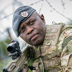 RAF Regiment Gunner in camouflage wearing blue beret with SA80 rifle