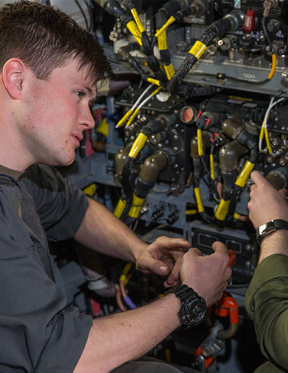 RAF Aviation Technician (Avionics) reconnecting equipment under guidance from RAF corporal
