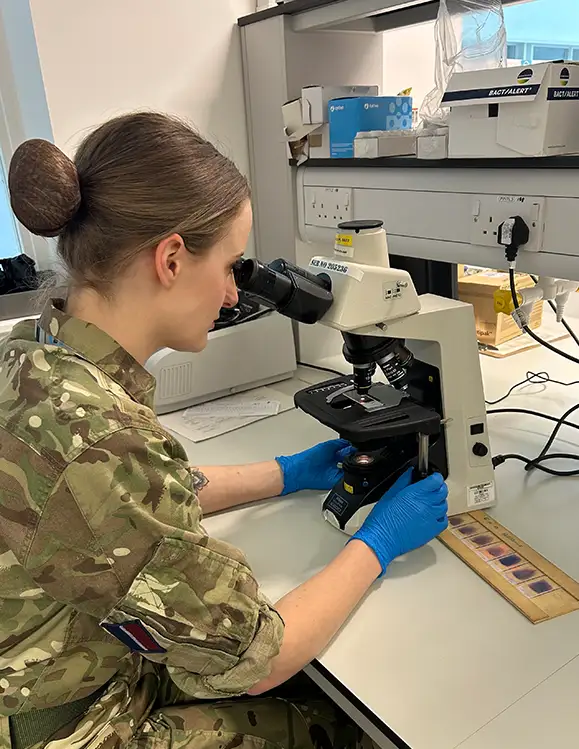 RAF Biomedical Scientist examining sample using microscope in laboratory