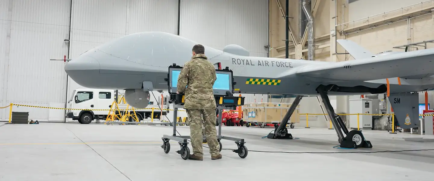 RAF Cyberspace Communications Specialist conducting diagnostic test at workstation accessing RAF Protector remotely piloted air system in aircraft hangar