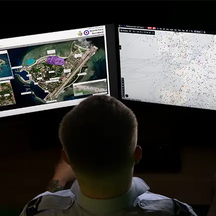RAF Intelligence Analyst studying aerial photograph of airfield on computer monitors