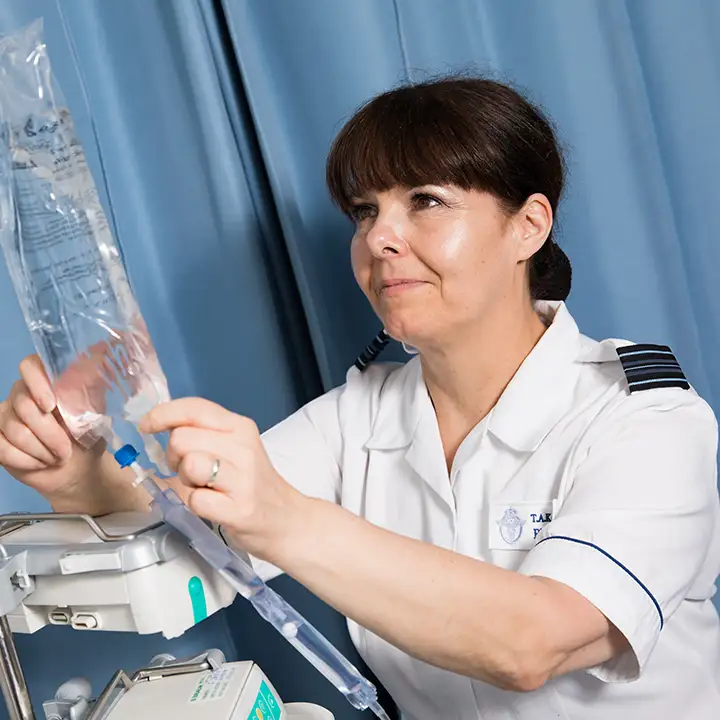 RAF Nursing Officer adjusting intravenous drip in patient treatment cubicle