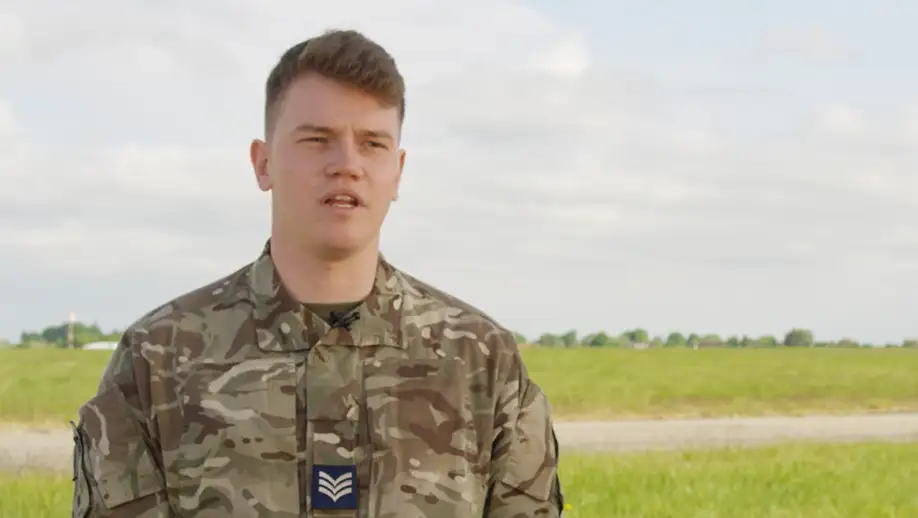 RAF Air Traffic & Weapons Controller stood on airfield explaining his role in this video