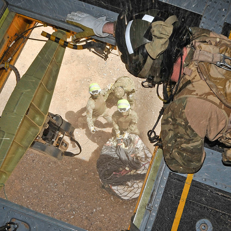 Weapons System Operator hooking up load under Chinook helicopter