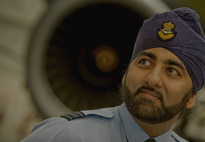 RAF Engineering Officer wearing turban stood in front of RAF Voyager engine in hanger